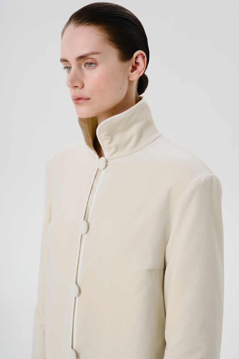 Ivory velvet coat by DELEGAN displayed on a model, showing the soft texture and classic coat silhouette.
