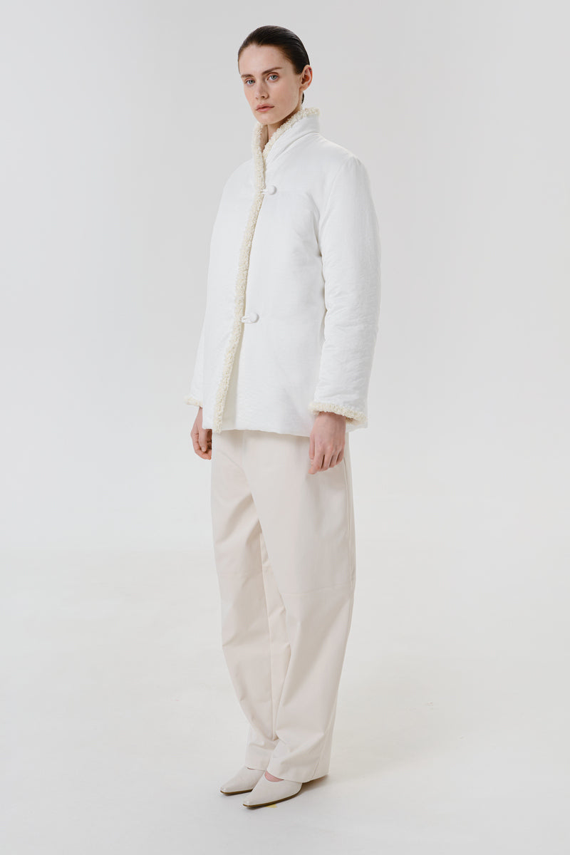 White DELEGAN jacket worn side view, stylish outerwear with a clean, modern design, perfect for casual or layered outfits.