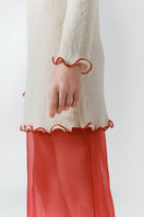 Red veil midi skirt by DELEGAN, shown from the side with flowing fabric and stylish design.