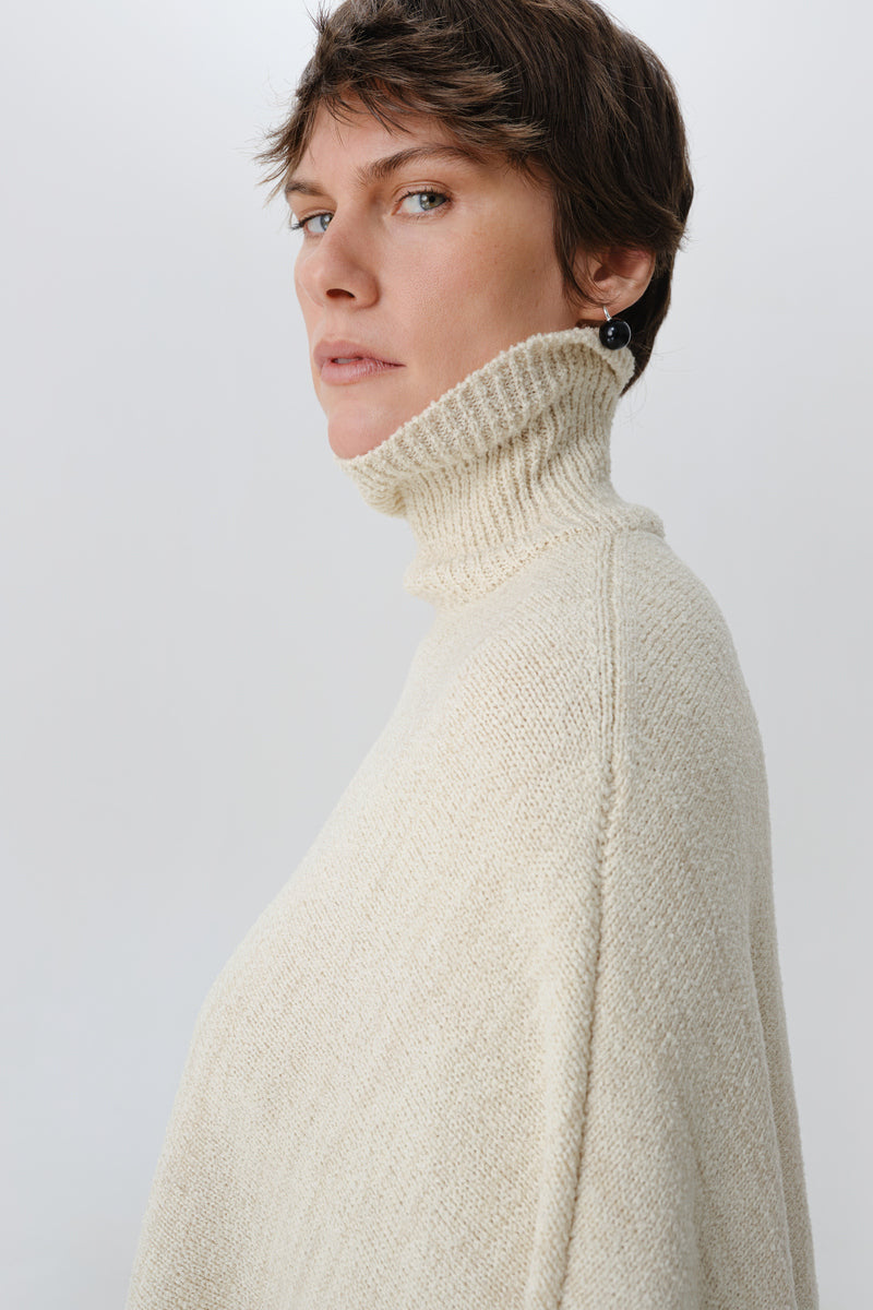 DELEGAN milk blush poncho cardigan worn side view, soft fabric with blush pink color, casual and cozy style for layering