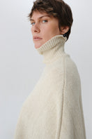 DELEGAN Milk Blush Poncho cardigan worn side view, soft fabric, cozy fit, stylish layering piece for casual or dressy outfits.