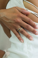 Gold-plated silver Nexus ring with sapphire and diamond accents on a female hand, by EDXÚ.