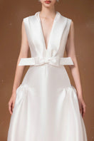 White pleated gown by HACCHIC COUTURE featuring flowing fabric and elegant design, perfect for formal occasions.