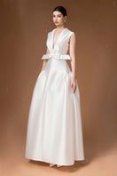 White pleated gown by HACCHIC COUTURE, elegant floor-length dress with flowing pleats and a sophisticated design.