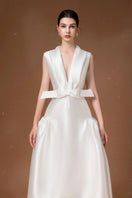 White pleated gown by HACCHIC COUTURE featuring elegant flowing fabric and a sophisticated design for formal occasions.