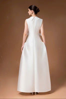 White pleated gown by HACCHIC COUTURE, elegant floor-length dress with flowing pleats and a sophisticated silhouette.