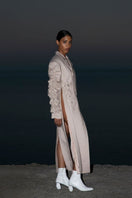 Beige crumple-sleeve trench coat by Blikvanger, shown on a hanger with textured fabric and classic design details.