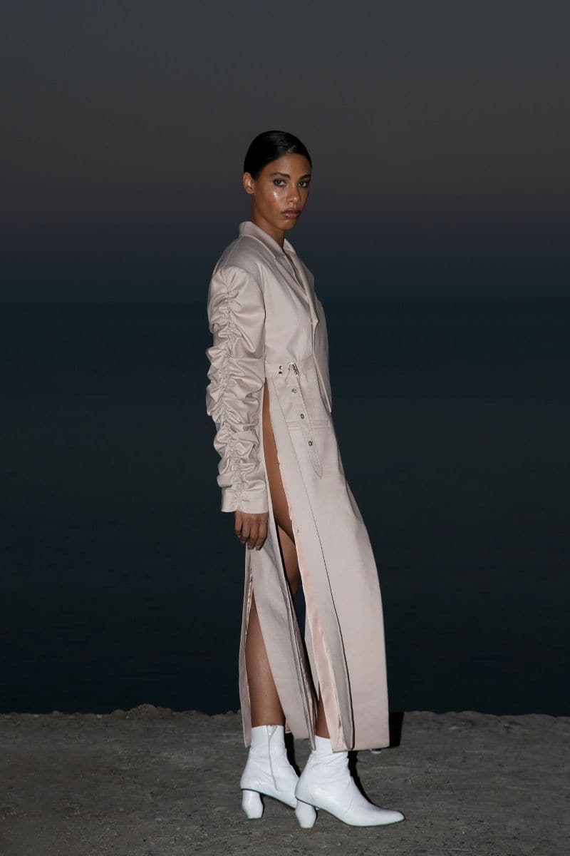 Beige crumple-sleeve trench coat by Blikvanger, shown on a hanger with textured fabric and classic design details.