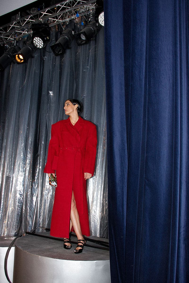 Full-length maroon coat by Blikvanger featuring a structured design, shown on a model with a tailored fit and classic style.