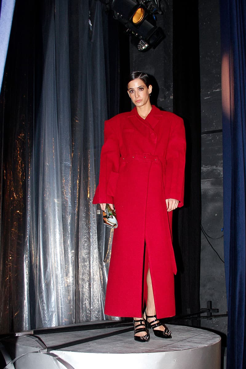 Full-length maroon coat by Blikvanger featuring a structured design, shown hanging on a hanger.