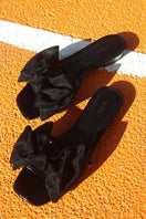 Black patent bow sliders by House of Atana, stylish flat sandals with bow embellishment, perfect for casual and chic summer looks.