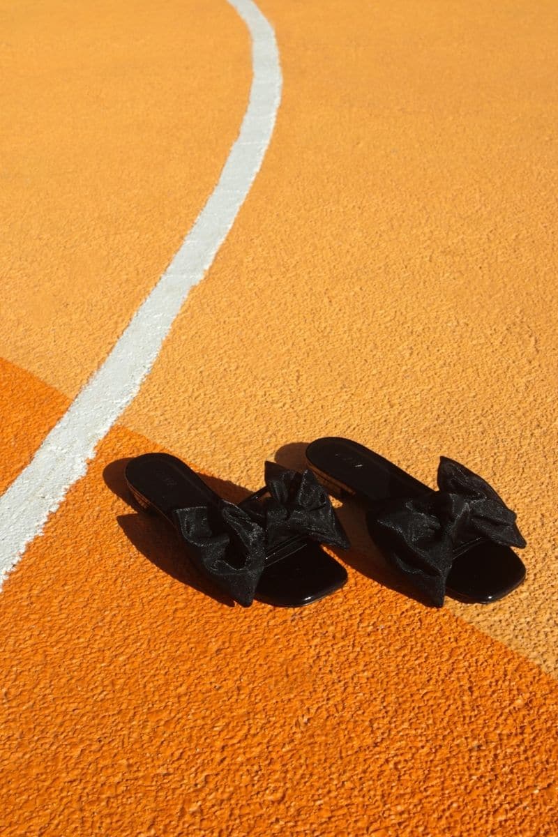 Black patent bow sliders flats by House of Atana with a stylish bow detail, perfect for casual or dressy summer wear.