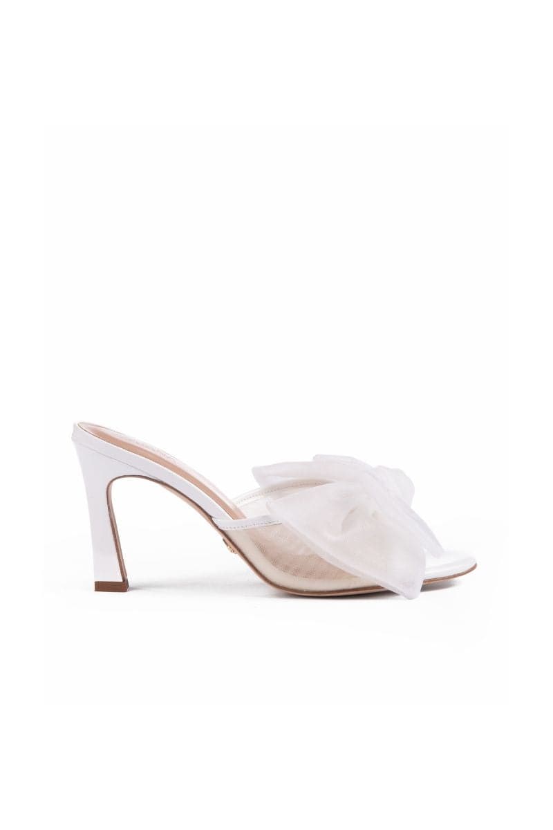 White patent bow mules sandals by House of Atana, featuring a sleek design and comfortable slip-on style.
