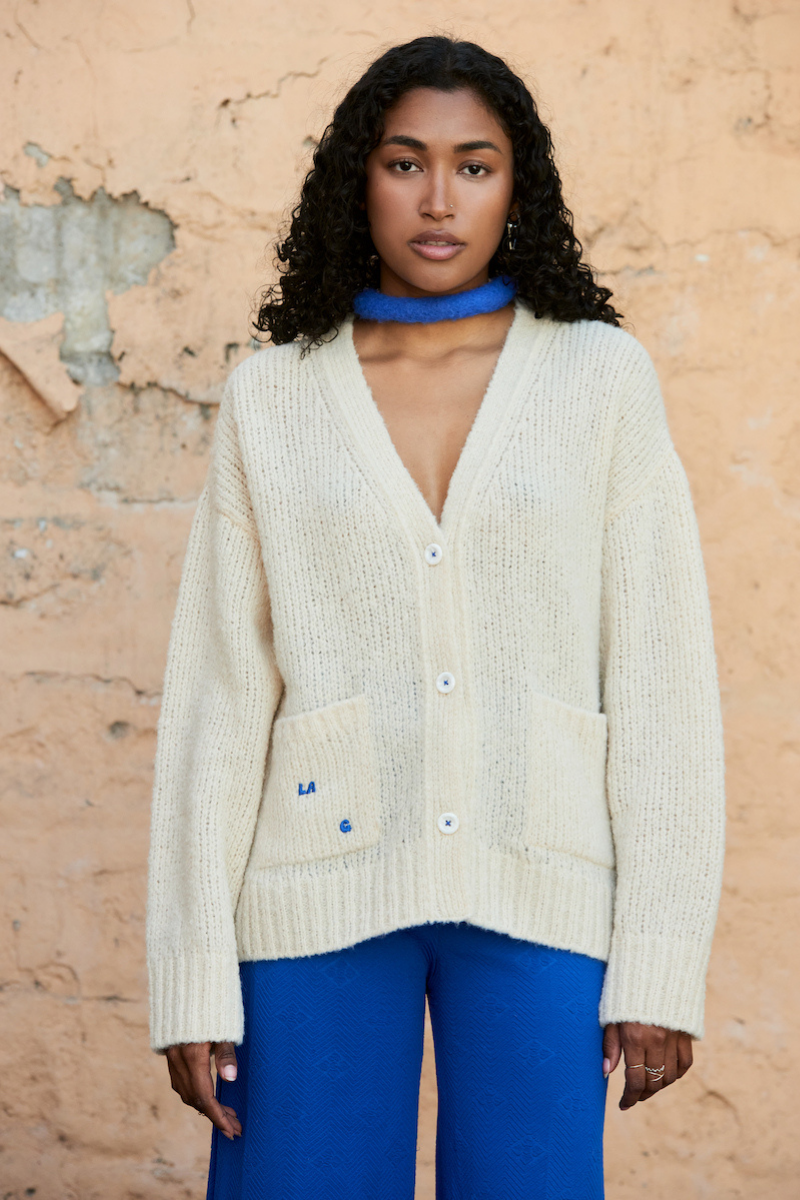 Cream knitted cardigan by La Granni, featuring a cozy, textured design with long sleeves and button closure.