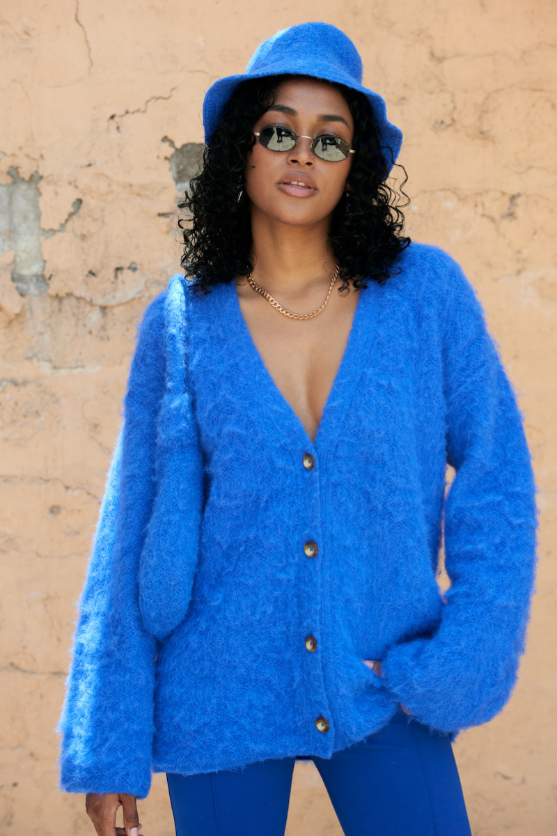 Blue knitted SURI cardigan by La Granni, featuring a cozy design and button details, displayed on a neutral background.