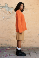 La Granni SURI knitted orange crewneck sweater displayed on a white background, showcasing its cozy, textured knit fabric.