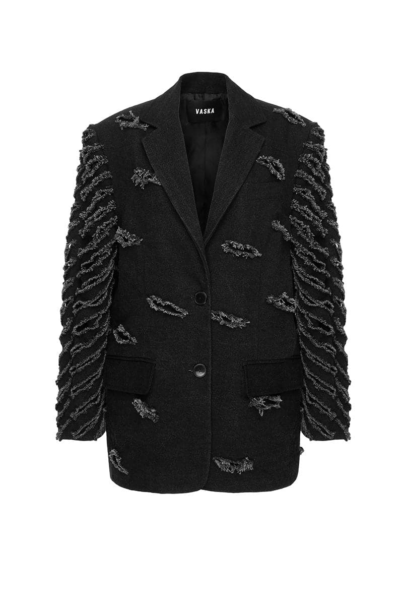 Black oversized distressed denim jacket by Vaska with frayed edges and a relaxed fit, displayed hanging on a wooden hanger.
