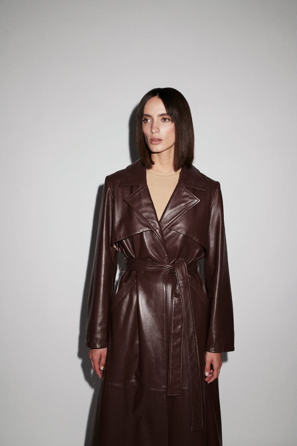 Brown leather trench coat by Verheyen, long coat with classic collar and button details, shown on a model.